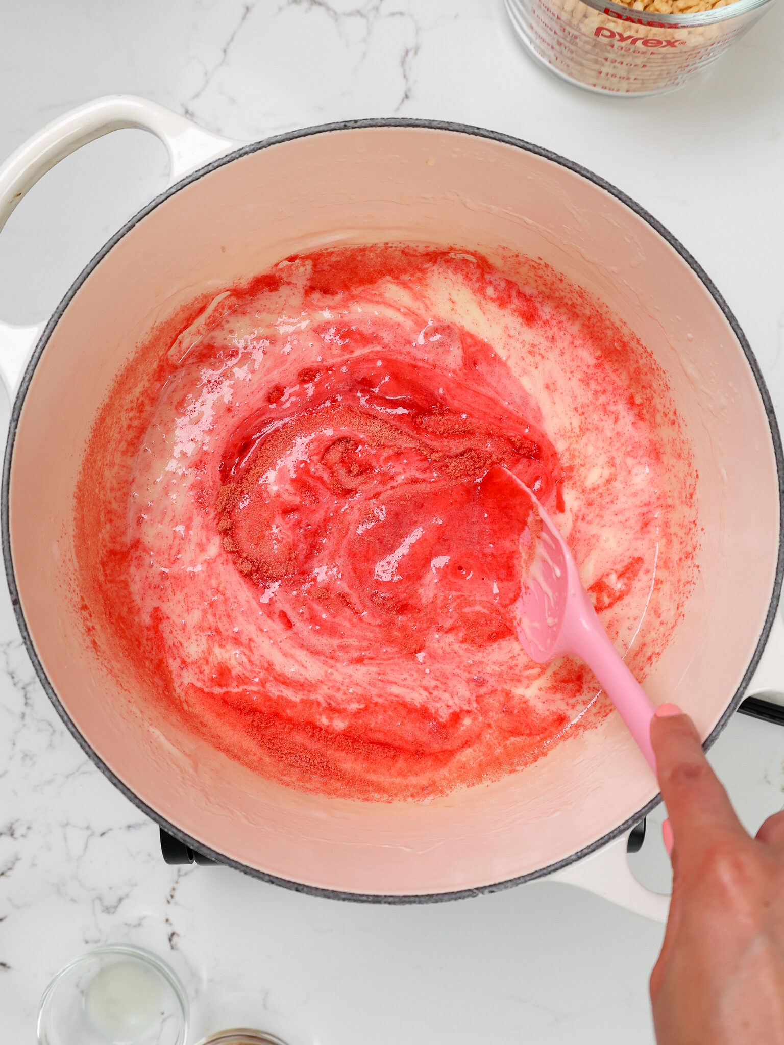 image of melted marshmallows, butter, and strawberry jello being mixed together in a large pot
