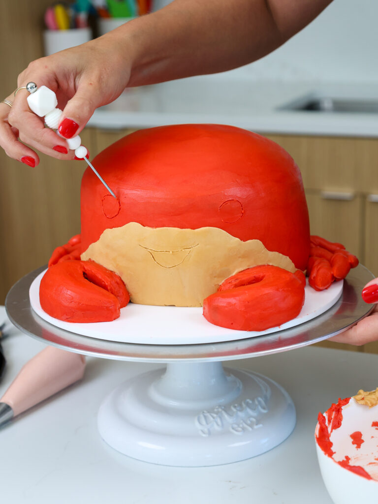 image of a face being traced onto a crab cake before piping it with buttercream frosting