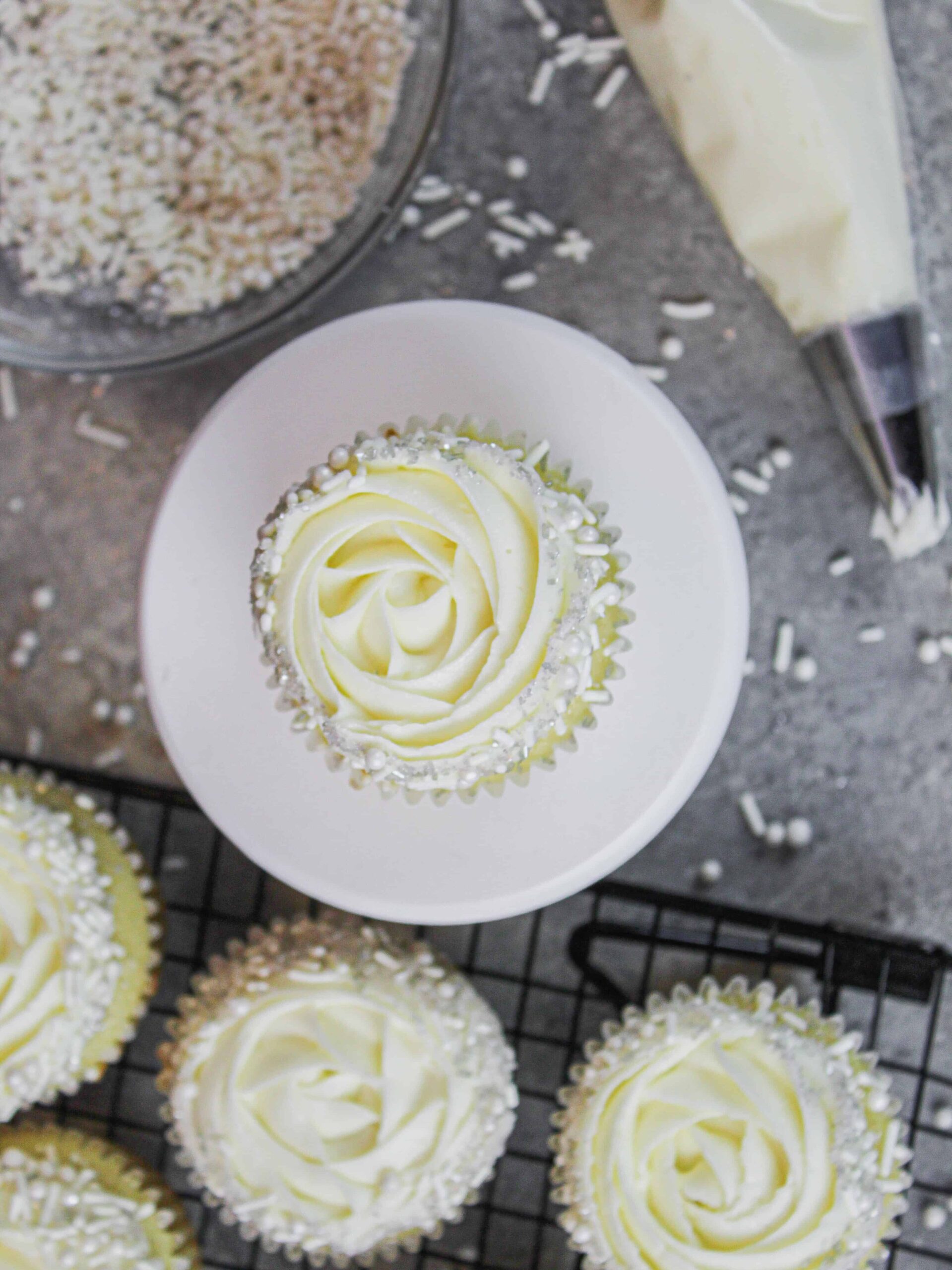 image of almond cupcakes decorated with a wilton 1m frosting tip and a fancy white sprinkle blend
