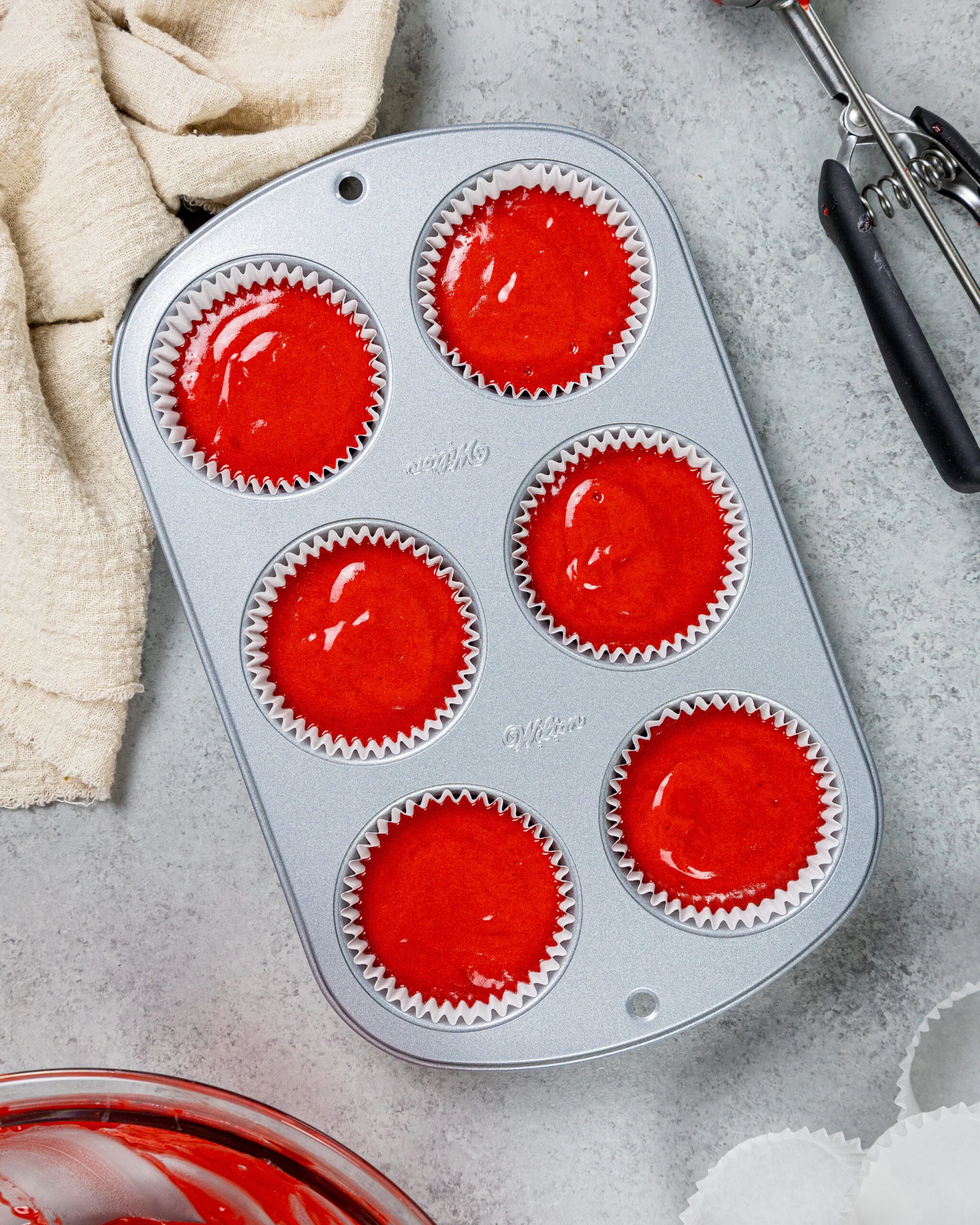image of red velvet cupcake batter that's been scooped into a lined muffin tin and are ready to be baked