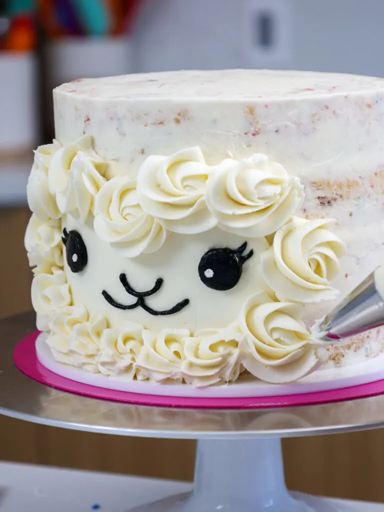 image of white buttercream being piped around a llama cake