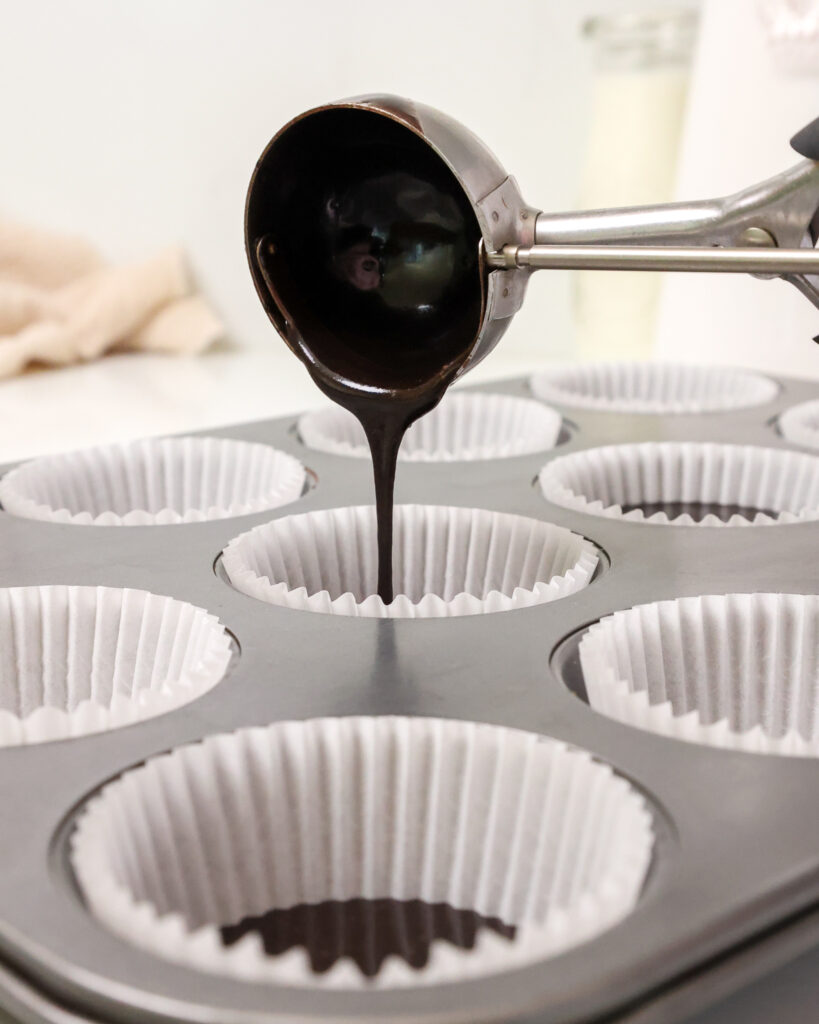 image of black velvet cupcake batter being poured into a cupcake liner