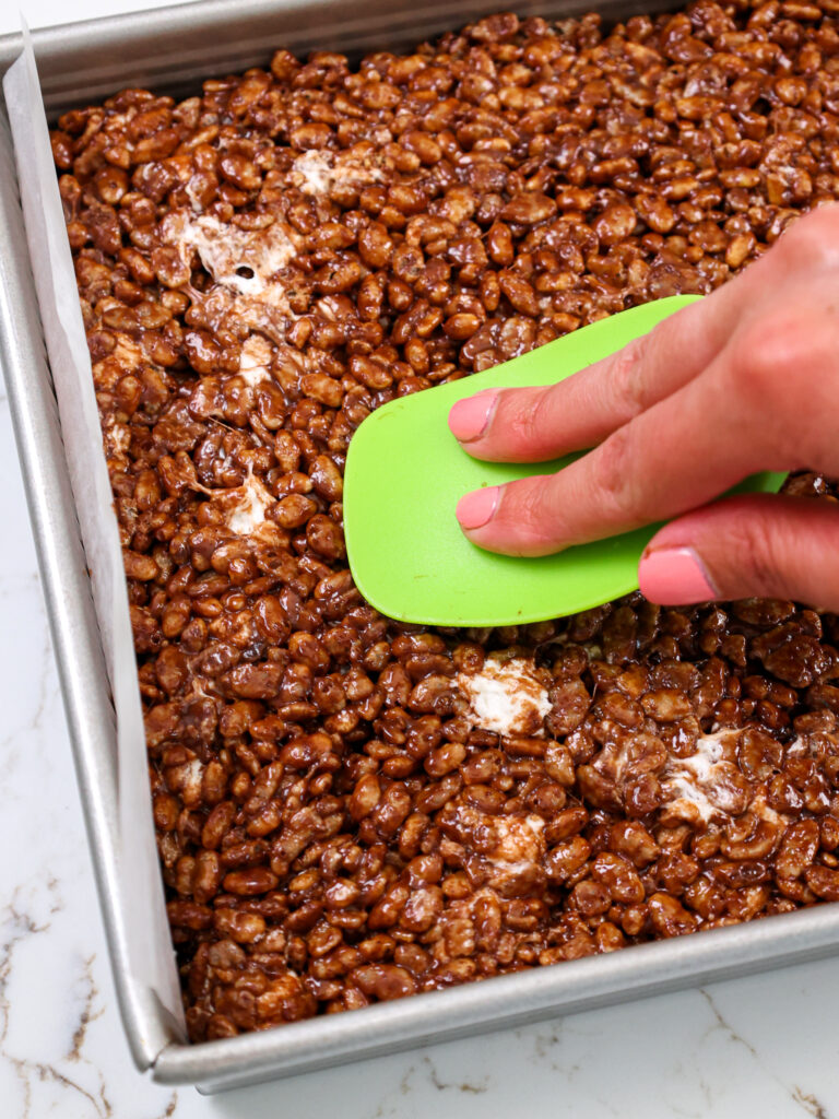 image of chocolate rice krispies being pressed into a pan