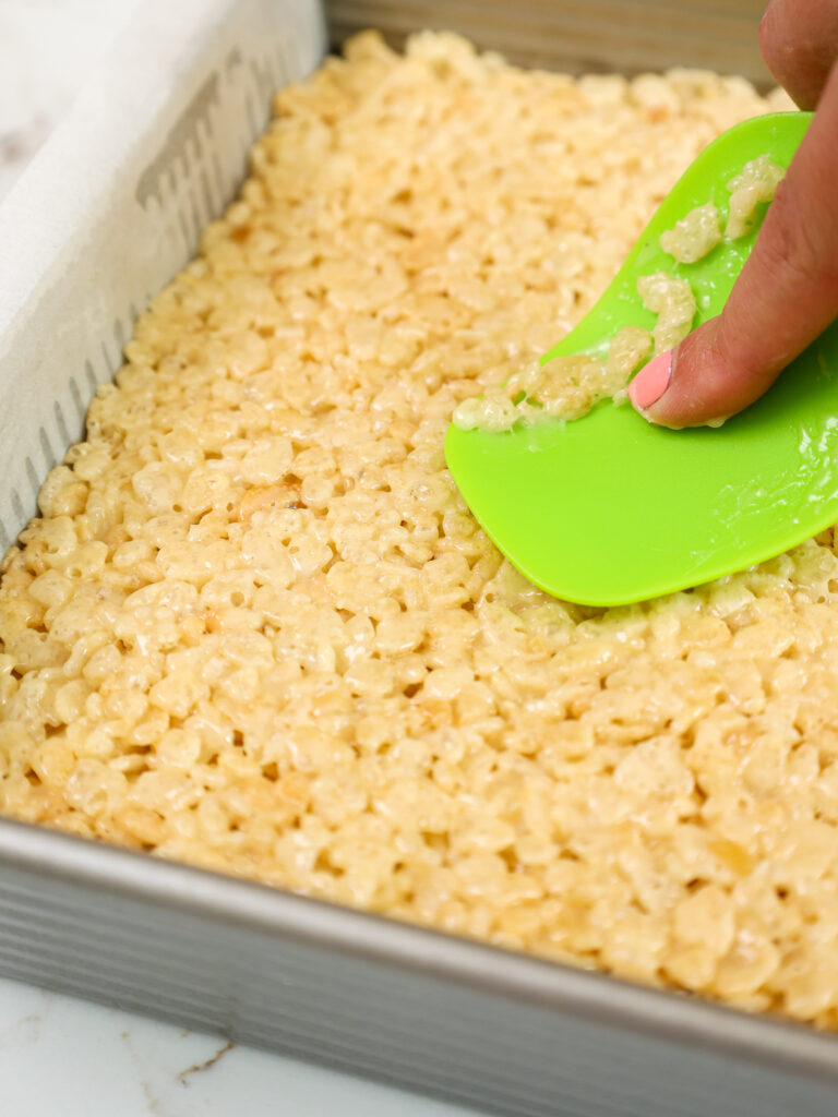 image of rice krispie treats being pressed into a square pan to cool off