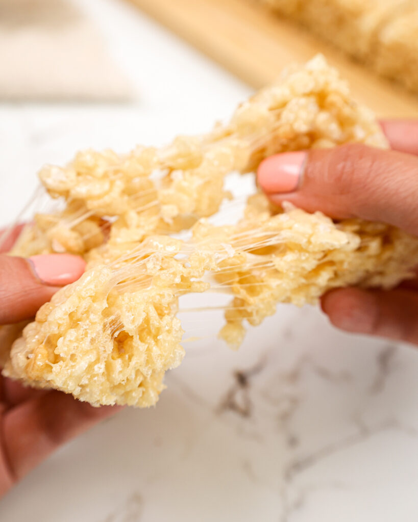 image of a gooey rice krispie treat being pulled apart to show it's soft, marshmallow texture