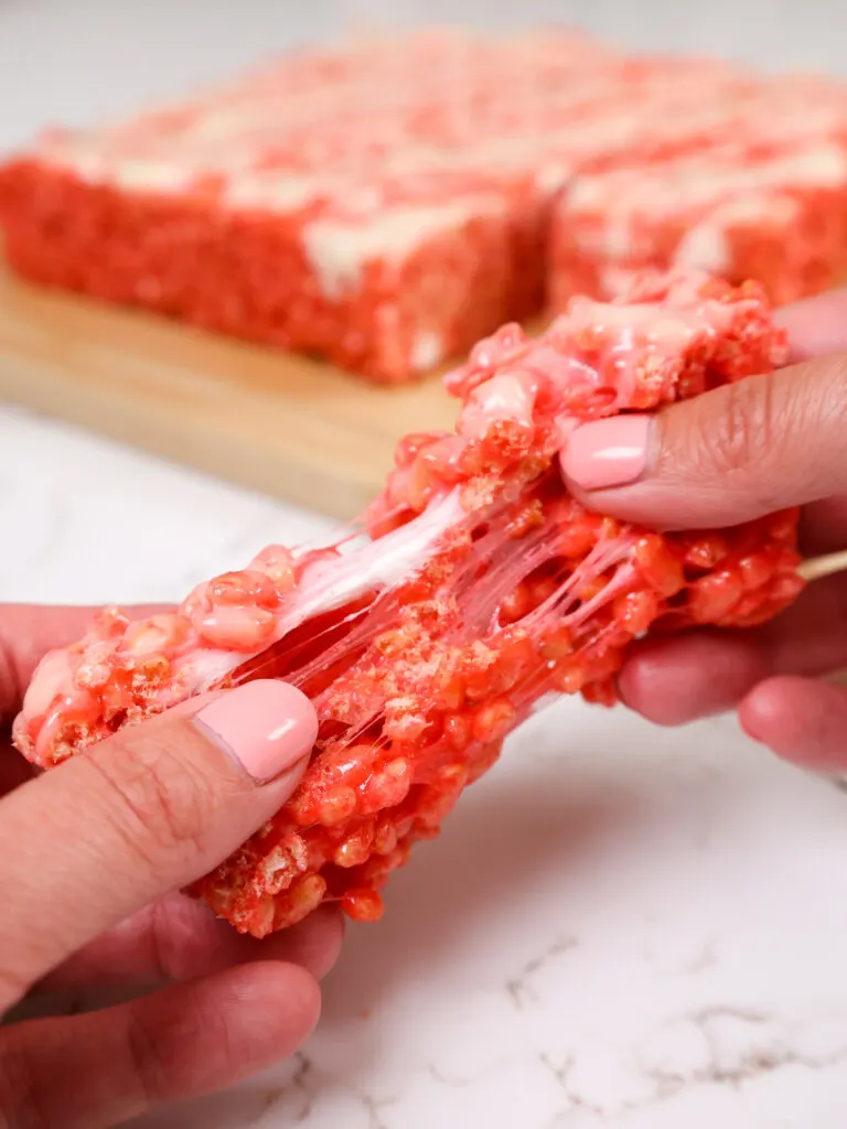 image of a strawberry rice krispie treat being pulled apart to show how gooey it is