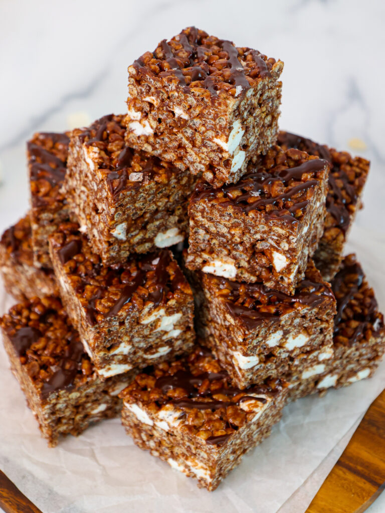 image of chocolate rice krispie treats that have been cut into square and stacked on a plate