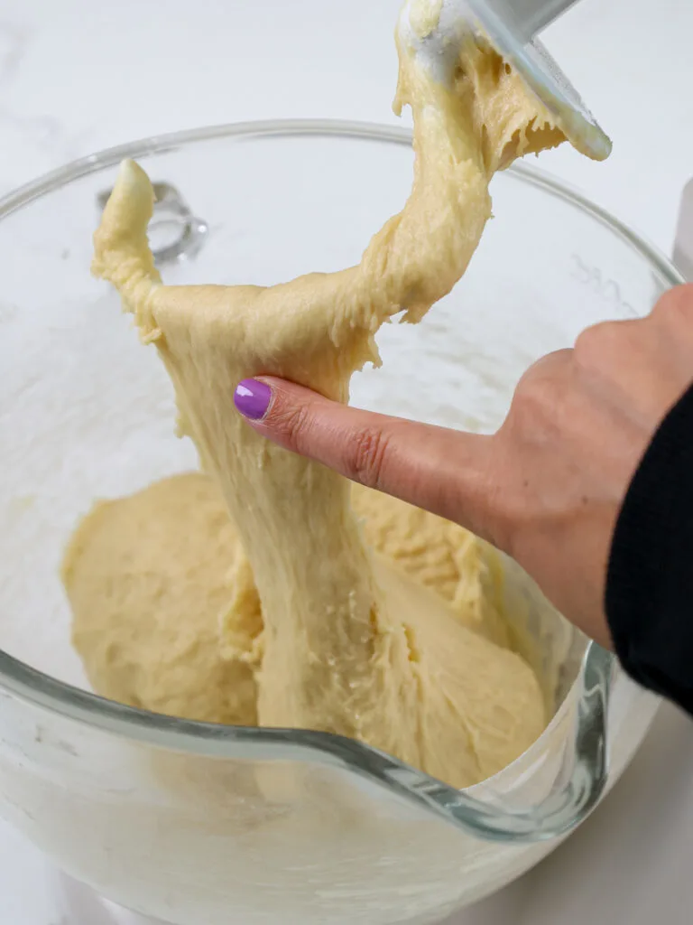 image of cinnamon roll dough being tested with a finger to see if it's the right consistency