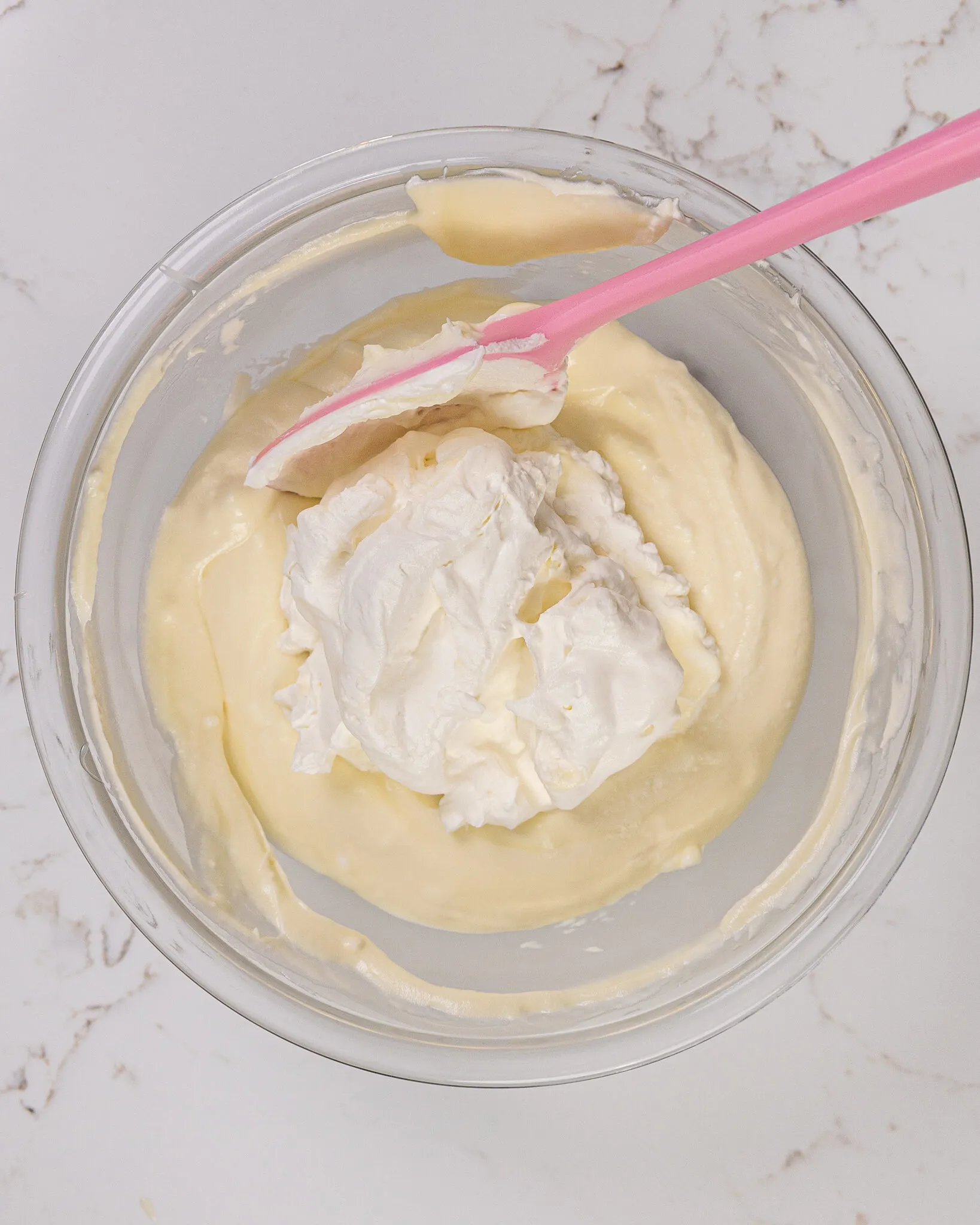 image of whipped cream being folded into white chocolate ganache to make a white chocolate mousse cake filling