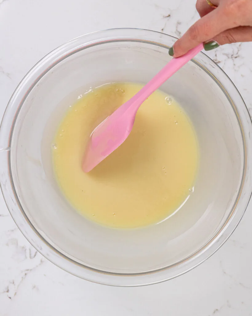 image of white chocolate and heavy cream being melted down together to make a thin ganache as a base for a white chocolate mousse