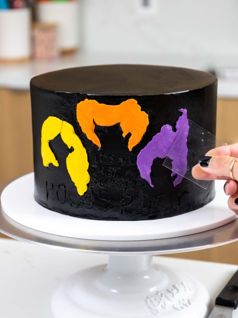 image of silhouettes of the Sanderson sisters being piped onto a hocus pocus cake with colorful buttercream