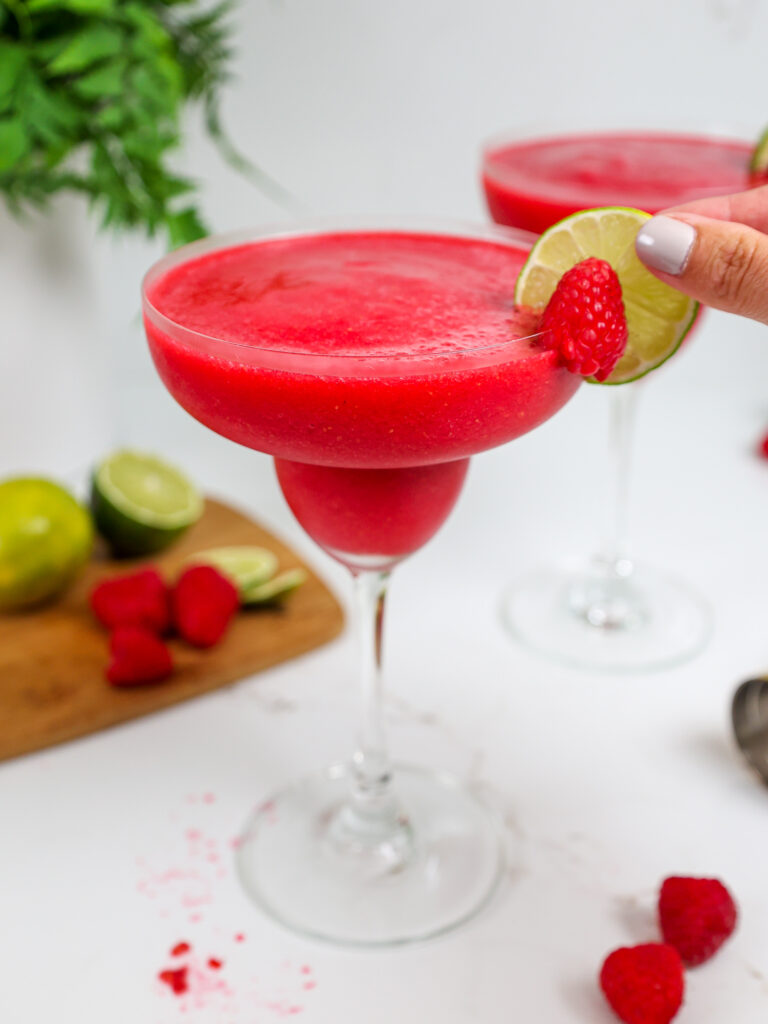 image of a lime slice being added to garnish a frozen raspberry daiquiri