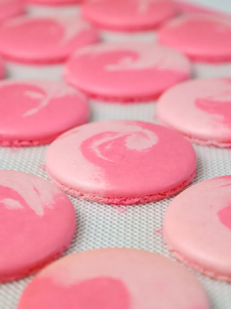 image of two-toned pink macaron shells that have been baked and have nice feet