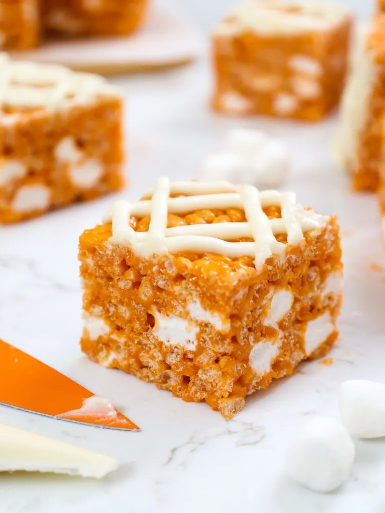 image of a pumpkin rice krispie treat that's been cut into squares and topped with cream cheese frosting