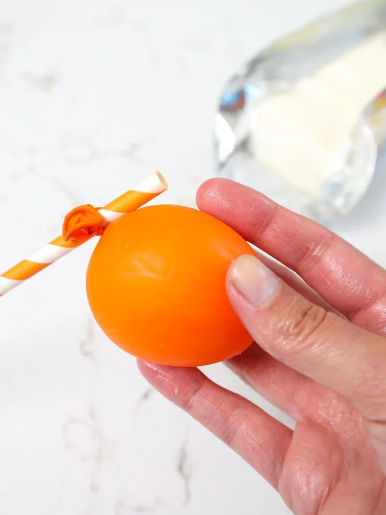 image of a small orange balloon being coated in shortening