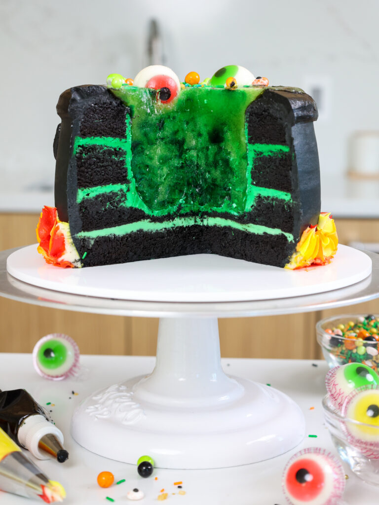 image of a cauldron cake that's been cut open to show it's spooky and cool green gelatin center