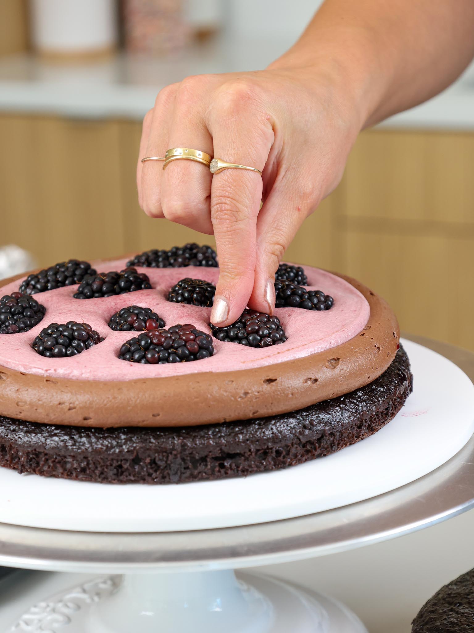 image of blackberries being add into the filling of a chocolate blackberry cake 