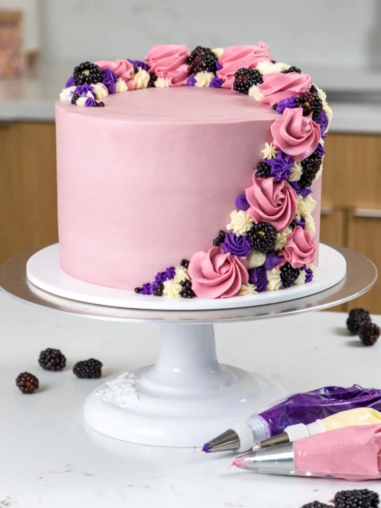 image of a beautiful blackberry mousse cake that's been decorated with buttercream swirls and fresh berries