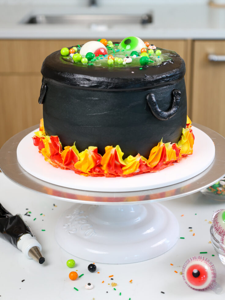 image of a cauldron cake made with black cocoa frosting and cake layers and a jello potion center