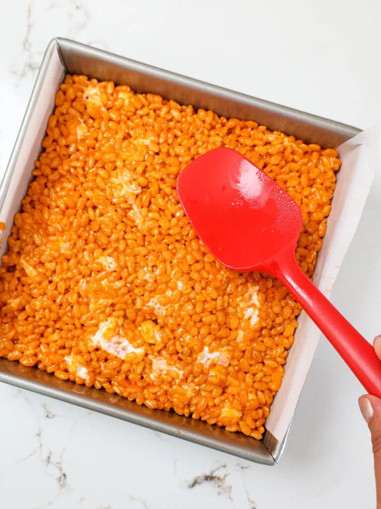 image of pumpkin rice krispie treats that are being pressed into a square pan to cool
