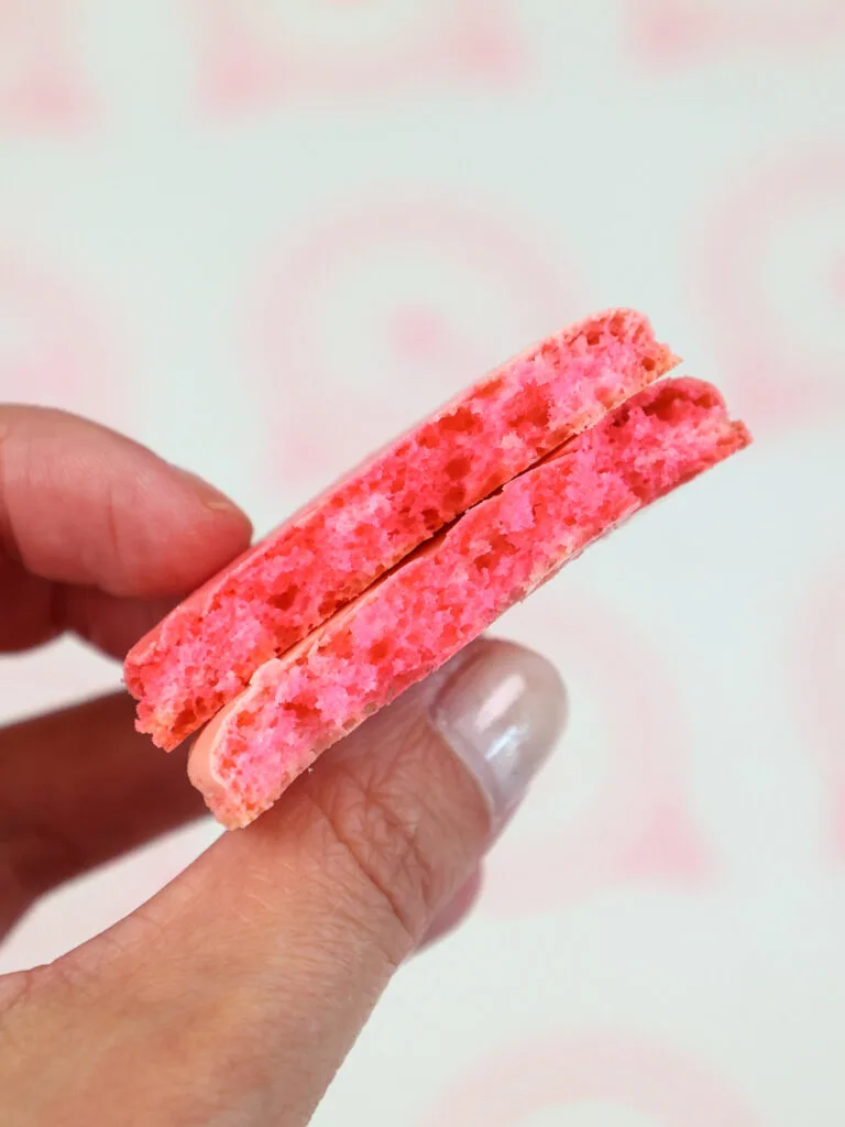 image of a pink macaron shells that's been cut in half to show that it has a full shell