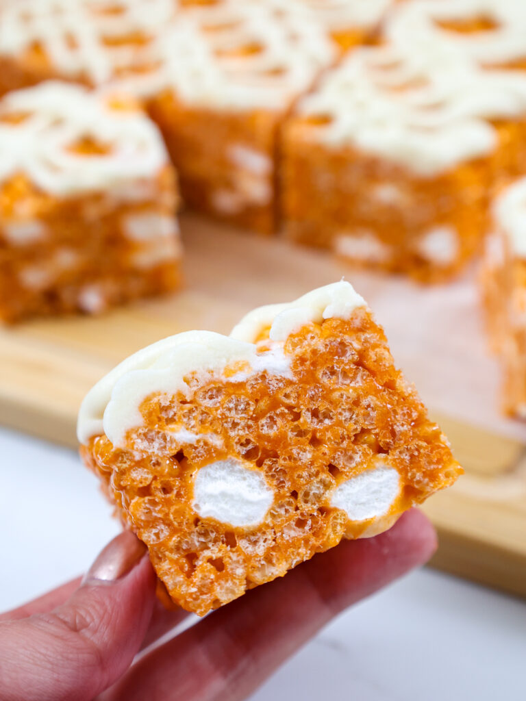 image of a pumpkin rice krispie treat being held up to show the mini marshmallows hidden inside it