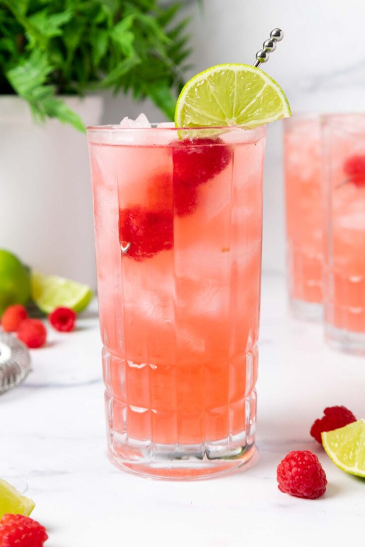image of a floradora cocktail that's been garnished with a lime wedge and fresh raspberries