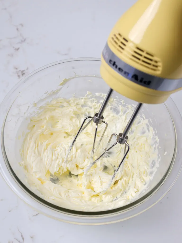 image of butter being beat with a hand mixer to make it smooth and incorporate air into it
