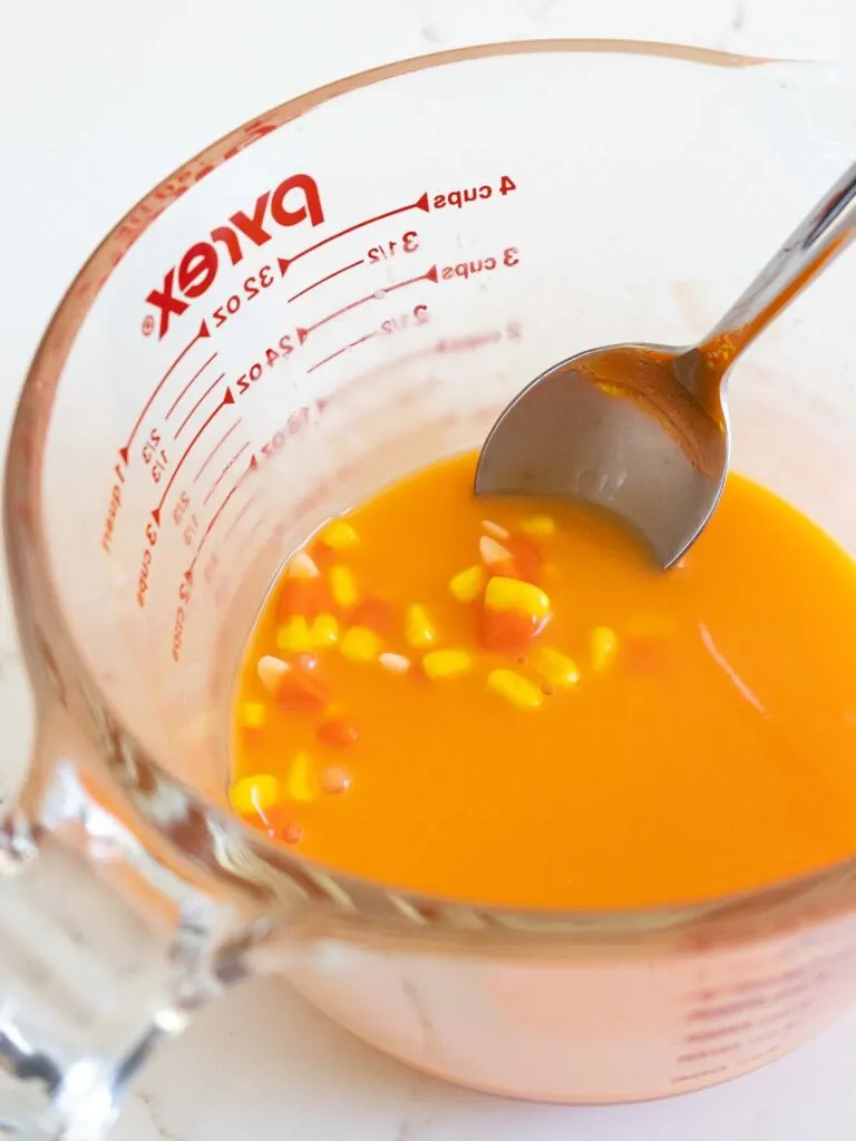 image of candy corn being melted down with heavy cream to dissolve and infuse the cream with candy corn flavor