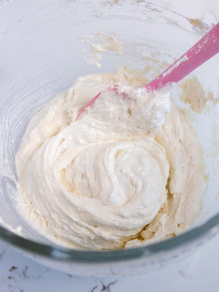 image of white macaron batter that's been partially mixed to incorporate the dry ingredients before being split into two bowls