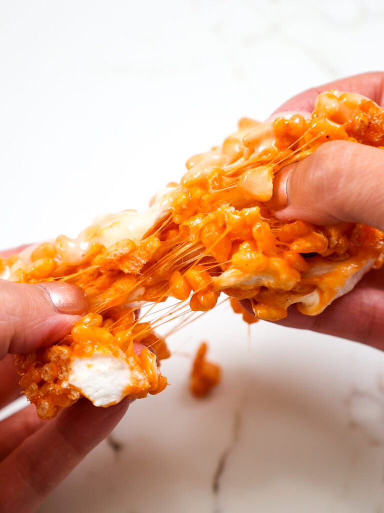 image of a pumpkin rice krispie treat being pulled apart to show how gooey and delicious it is