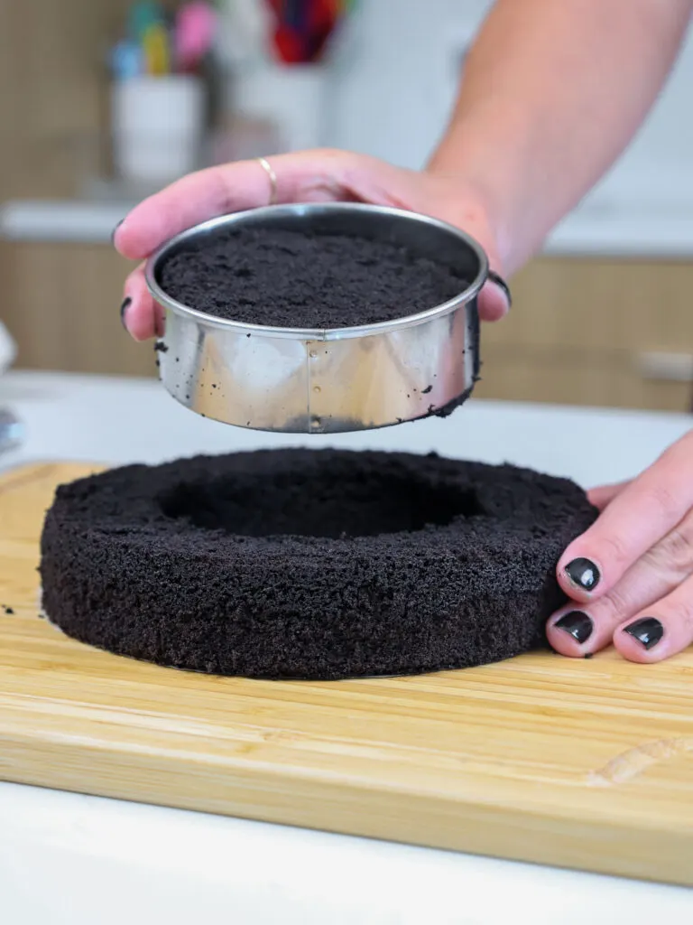 image of a circle cutter being used to remove the center of a black cocoa cake layer