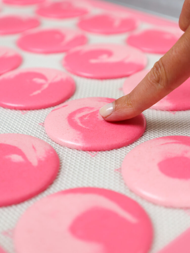 image of a pink macaron shell that's been rested and is ready to be baked