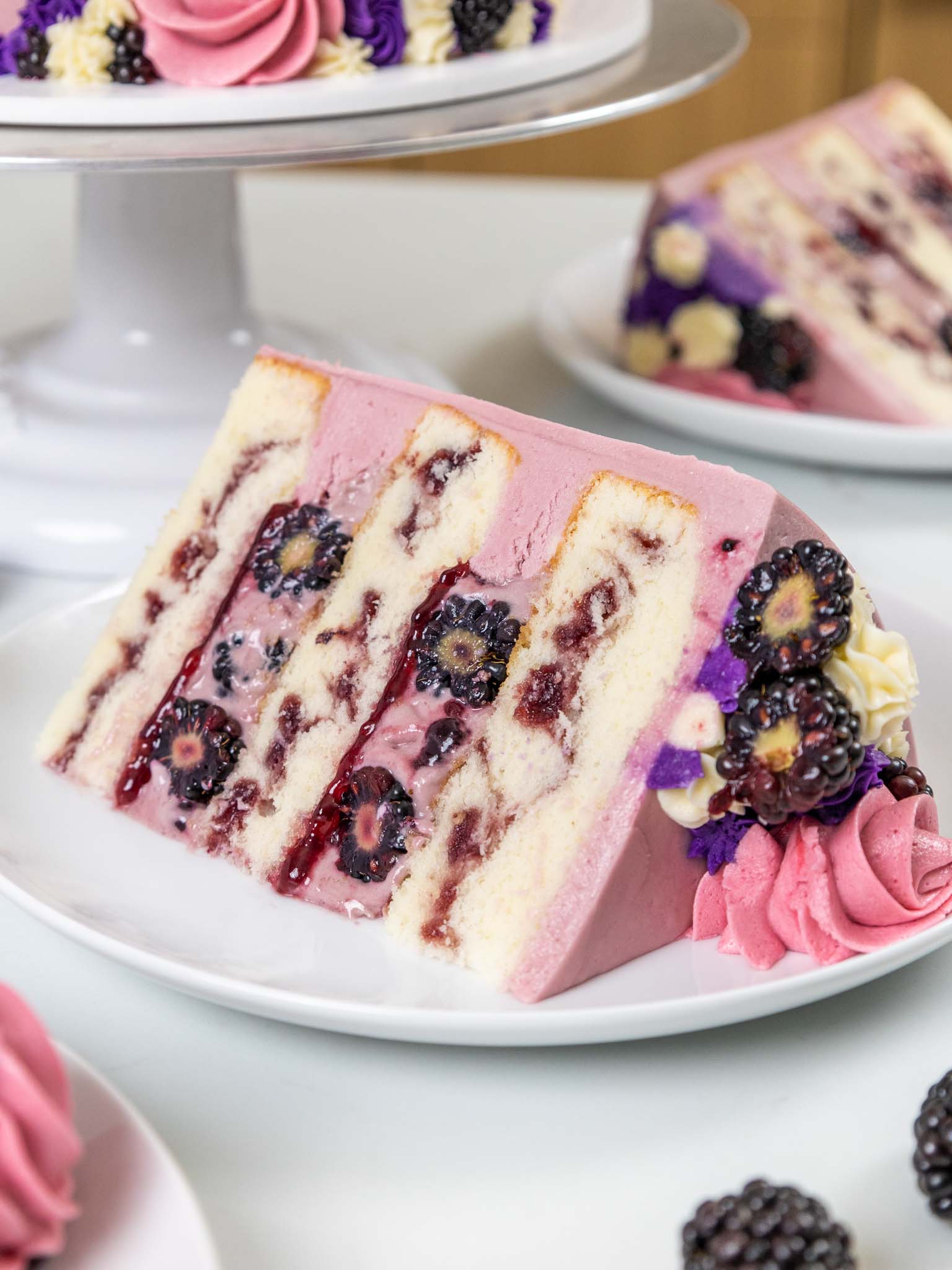 image of a blackberry mousse cake that's been cut and a slice has been plated showing it's delicious filling