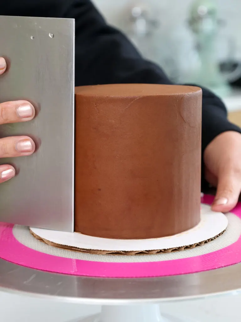 image of chocolate buttercream being smoothed onto a 4-inch chocolate cake