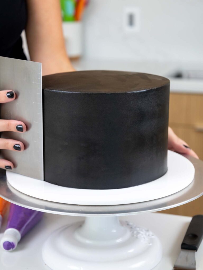 image of black buttercream being smoothed onto a 7-inch layer cake