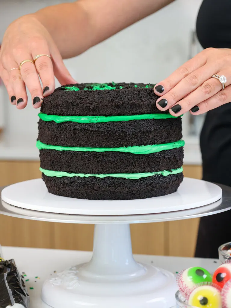 image of black cocoa cake layers being stacked with green buttercream