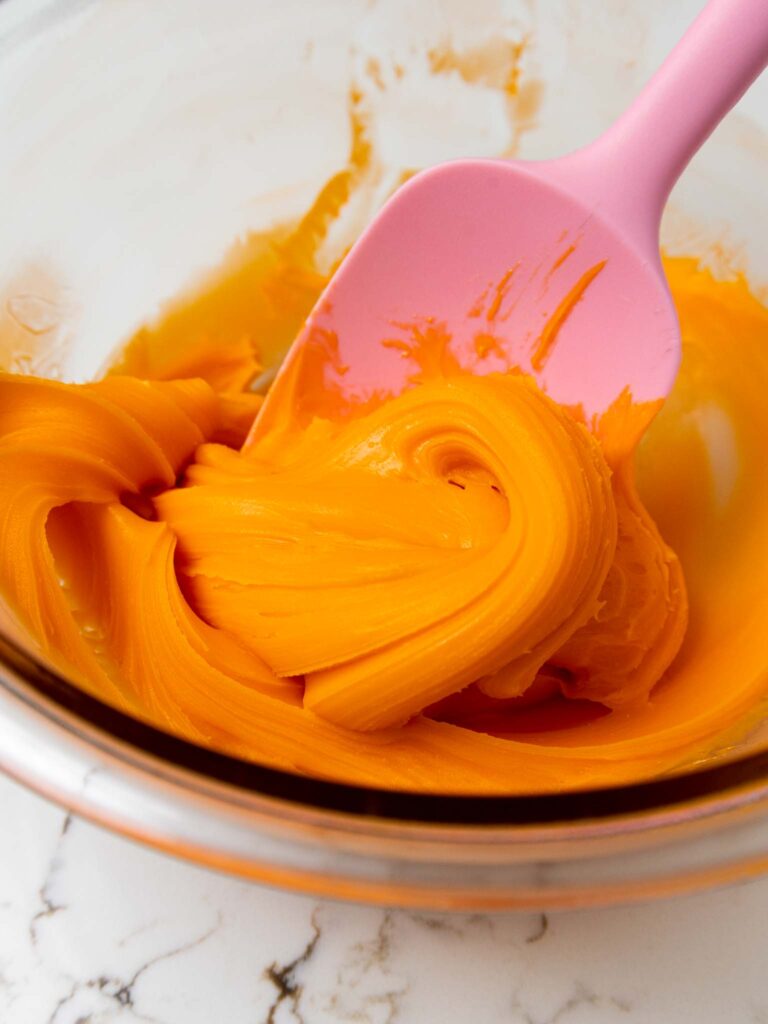 image of set candy corn ganache being stirred in a bowl before being placed in a piping bag