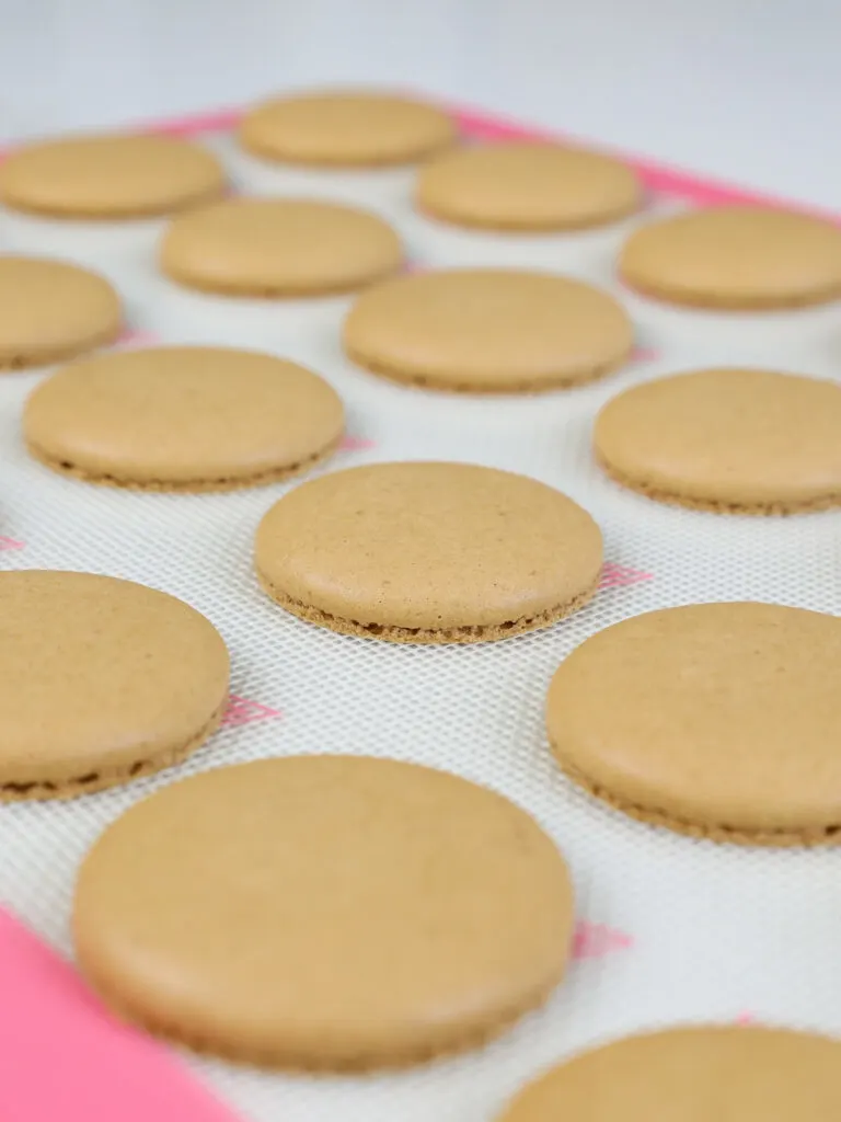 image of baked chocolate macaron shells cooling off on a silpat mat