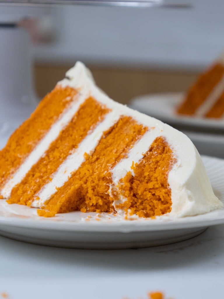 image of a slice of moist pumpkin layer cake that's been cut into to show how tender the cake layers are