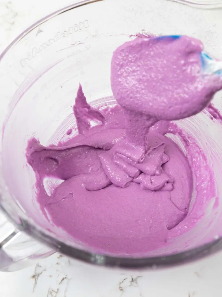 image of purple macaron batter that's been folded until thick ribbons run off the spatula when it's lifted