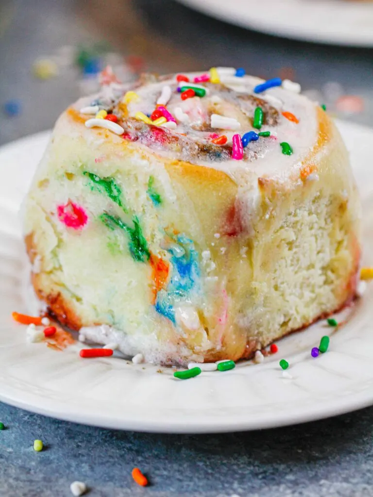 image of a funfetti cinnamon roll made with sprinkles and topped with vanilla icing