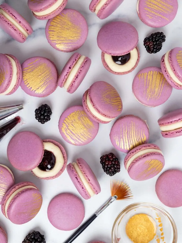 image of blackberry macarons that have been filled with blackberry jam and decorated with a brush of edible gold paint