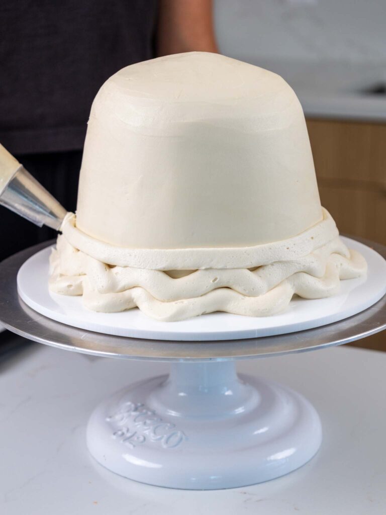 image of a ghost cake being frosted with buttercream frosting to make it have a cute ruffled base
