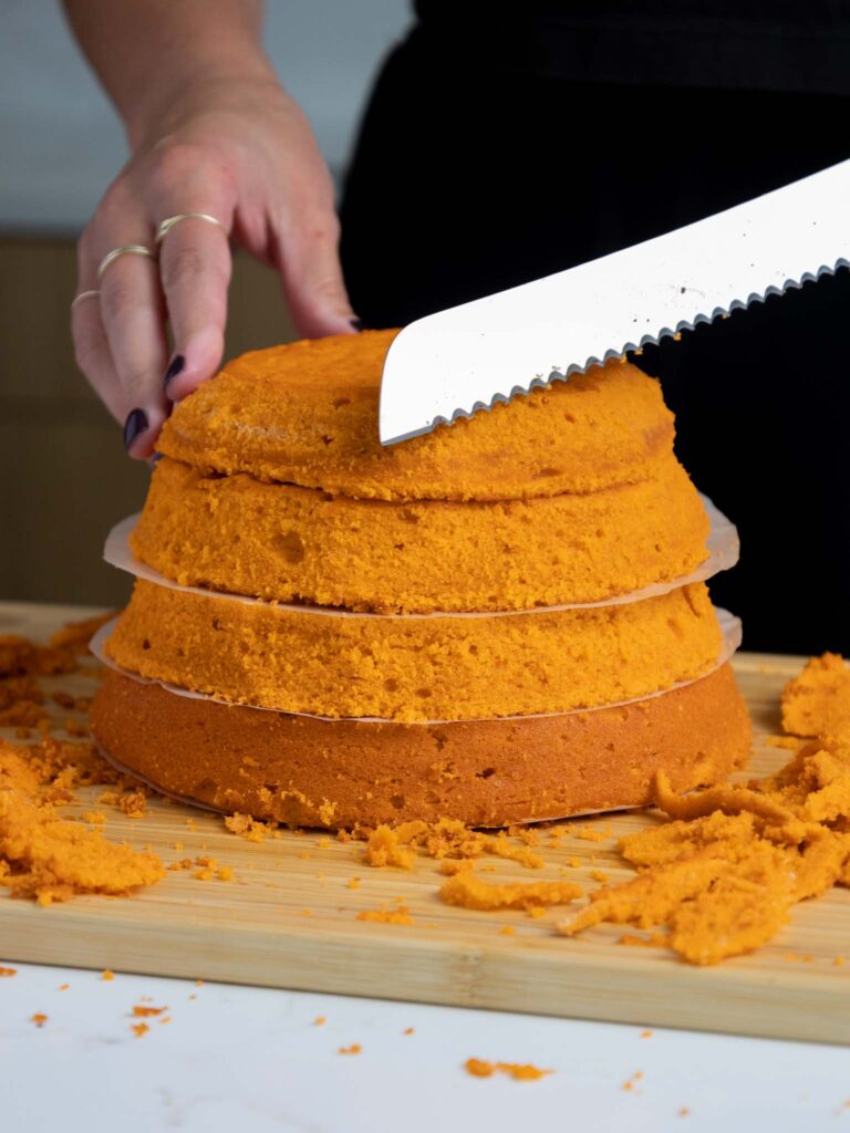 image of pumpkin cake layers being trimmed with a serrated knife