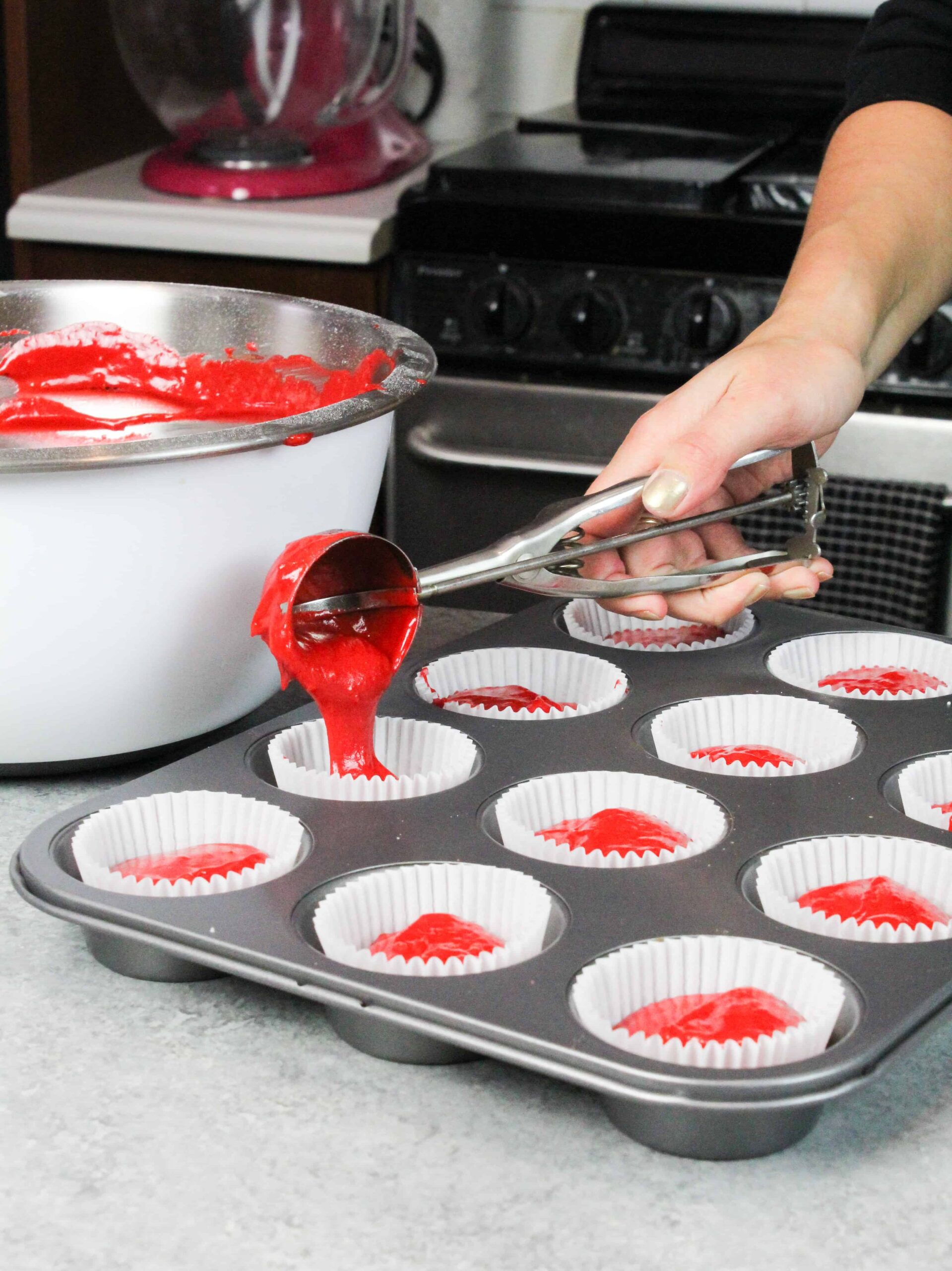 image of scooping red velvet cupcake batter into cupcake liners