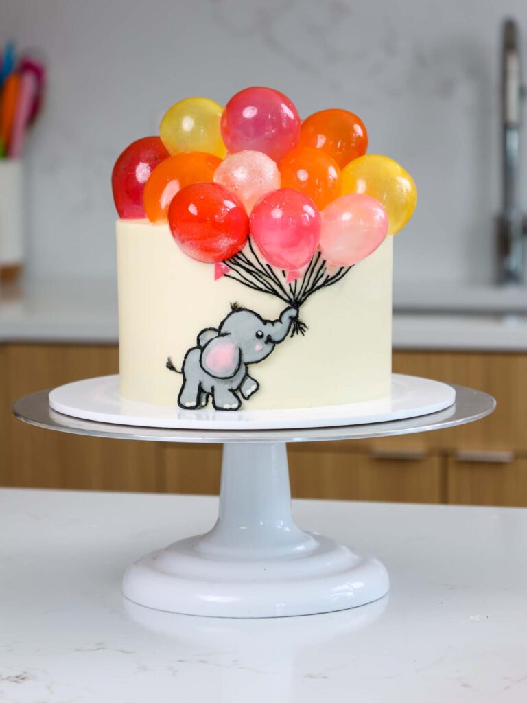 image of a cute baby shower cake that's been decorated with a baby elephant and gelatin balloons