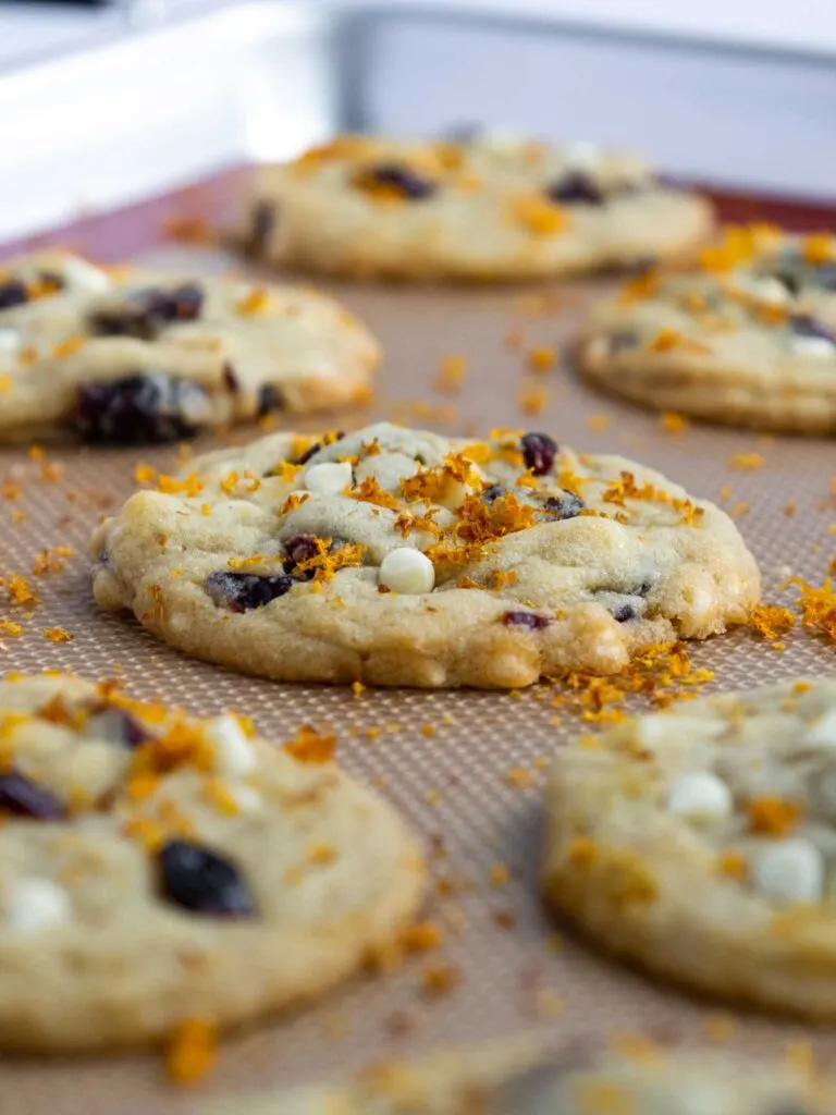 image of orange cranberry white chocolate cookies that have finished baking and are cooling on a silpat mat