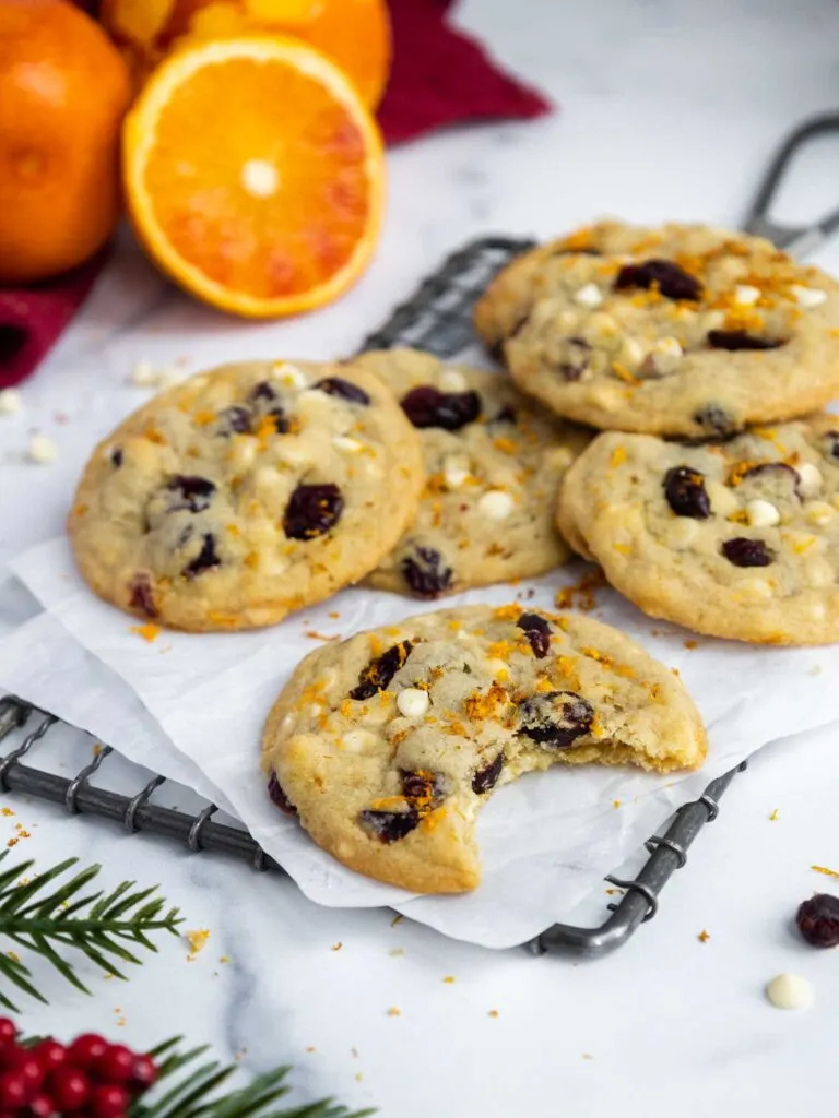 image of a white chocolate cranberry orange cookie that's been bitten into to show how soft and tender the cookies are