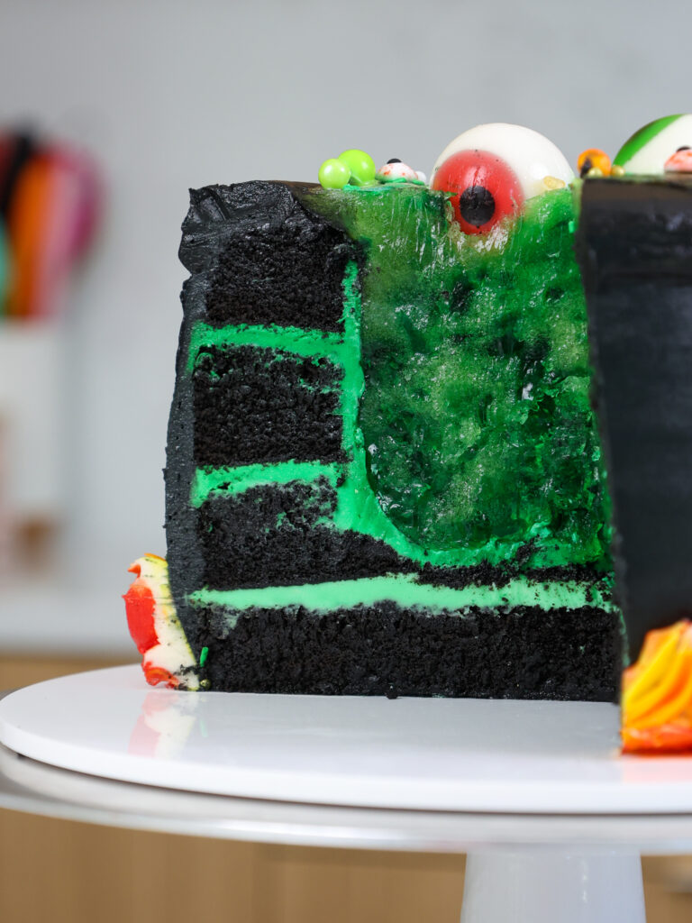image of a cut into cauldron cake that has a spooky gelatin center that's green to look like a potion